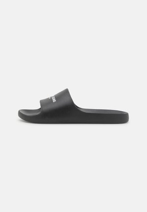 Sort slip-on sandal med bred rem, der viser hvid og rød tekst, flad sål, designet til afslappet brug.