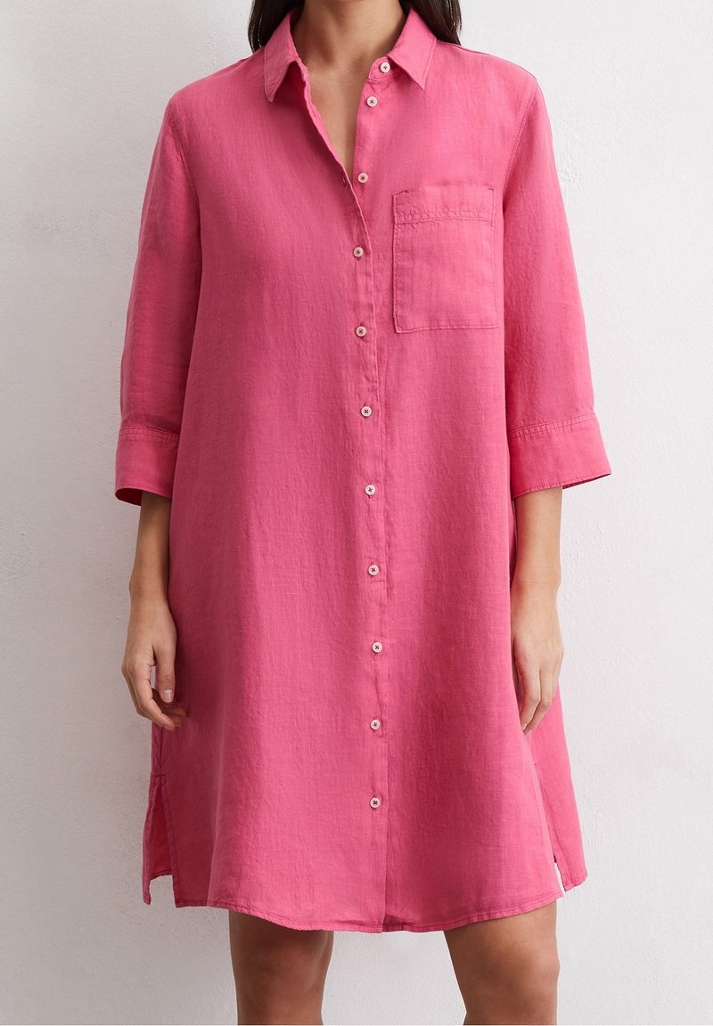 Różowa, lniana sukienka koszulowa z zapięciem na guziki z przodu, kołnierzykiem i kieszenią. Posiada długie rękawy z podwiniętymi mankietami oraz boczne rozcięcia dla łatwości ruchu.