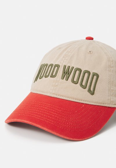 Beige baseball cap med rød skygge, med grønn "WOOD WOOD" brodering på fronten. Laget av bomull med en teksturert finish.