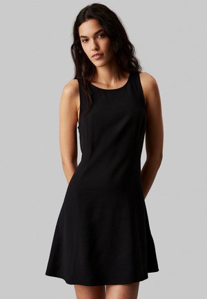 Vestido negro sin mangas con un cuerpo ajustado y falda acampanada. Hecho de tela suave con escote redondo y sin herrajes visibles.