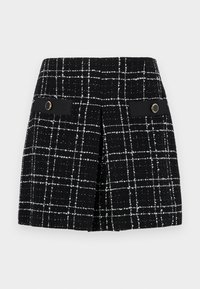 Black and white plaid skirt made of textured fabric, featuring two front pockets with black accents and circular gold hardware.