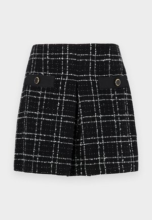 Svart og hvit rutet skjørt laget av teksturert stoff, med to frontlommer med sorte detaljer og sirkulær gullhardware.