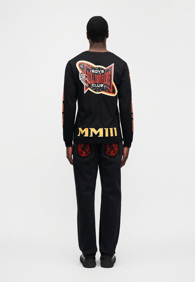 Μαύρο πουκάμισο μακρυμάνικο με πολύχρωμο γραφικό "Boys Billionaire Club" στην πλάτη. Μαύρα τζιν με κόκκινη κεντητή φιγούρα αστροναύτη στις τσέπες. Μαύρα παπούτσια.