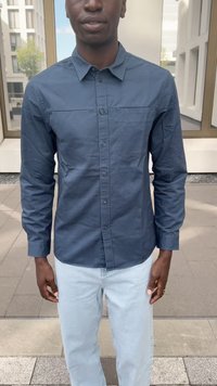 Chemise boutonnée à manches longues bleu marine avec une poche poitrine, en tissu uni, et un ourlet arrondi, assortie à un jean bleu clair.