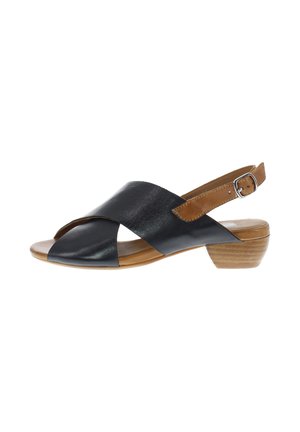 Black leather open-toe sandal with crisscross straps, adjustable tan ankle strap, and low stacked wooden heel.