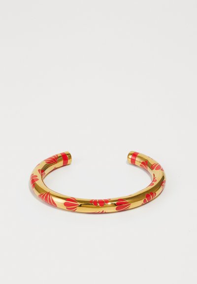 Pulsera de puño de color dorado con patrones florales rojos, acabado metálico suave y extremos abiertos redondeados con una textura brillante.