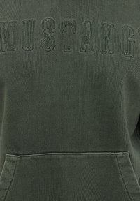 Olivengrøn sweatshirt med tekstureret stof, "MUSTANG" broderet i matchende farve på brystet, med frontlomme og ribstrikkede manchetter.