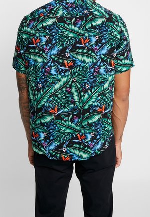 Chemise à manches courtes avec un fond noir orné de feuilles tropicales vertes, de fleurs orange et d'accents violets, fabriquée dans un tissu léger.
