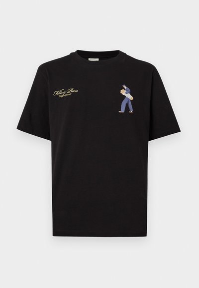 Μαύρο βαμβακερό μπλουζάκι με κοντά μανίκια, με κεντητό σχέδιο ενός ατόμου που μεταφέρει ψωμί και χρυσό κείμενο πάνω από την εικόνα.