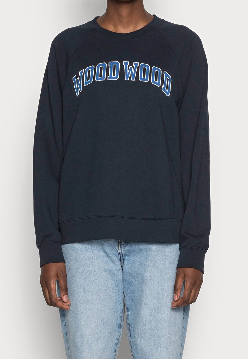 Marinblå crewneck-tröja med "WOOD WOOD" i vita och blå bokstäver. Tillverkad av mjukt tyg med ribbade muddar och en nederkant. Avslappnad passform.