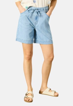 Svetlomodré denimové šortky s previazaným pásom, nosené s bielym topom a béžovými slip-on sandálmi s dvojitými prackami.