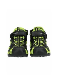 Czarne buty Geox w kolorze limonkowym z siateczkowym wierzchem, gumową podeszwą, regulowanym zapięciem na rzep oraz elastycznymi sznurówkami. Posiadają oddychającą konstrukcję.