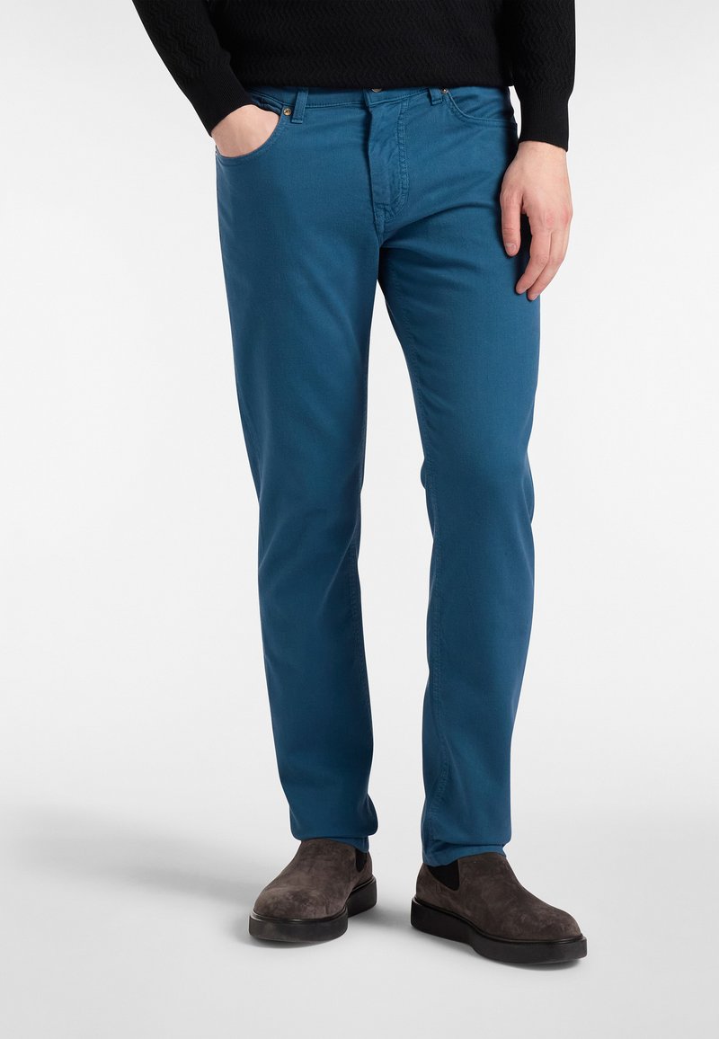 Modri bombažni hlače slim fit, sprednji žepi in kontrastni šivi. V kombinaciji z temno z naravnimi antilop čevlji do gležnjev.