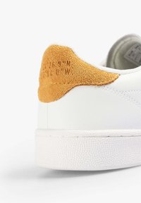 Witte leren sneaker met een lichtbruine suede hiel tab, met geperst coördinaten. Voering van rubber voor grip.