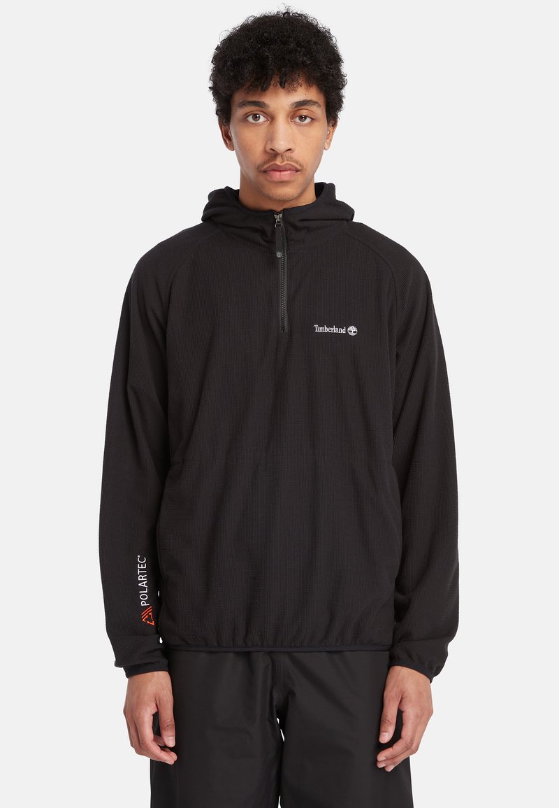 Zwarte pullover capuchonjack gemaakt van een gestructureerde stof met een halve ritssluiting, voorzien van een Timberland-logo en Polartec®-branding op de mouw.