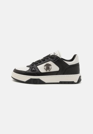 Sneaker in bianco e nero con tomaia in pelle testurizzata, punta perforata, logo laterale e suola robusta bianca con accenti neri.
