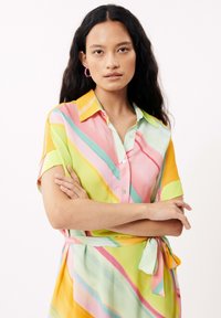 Robe à manches courtes avec boutonnière et ceinture à nouer, ornée de bandes lumineuses et ondulées en rose, jaune, vert et bleu sur un fond clair.