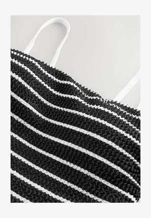 Tessuto a strisce bianco e nero con un design testurizzato e arricciato. Presenta spalline bianche. Lo sfondo è grigio chiaro.