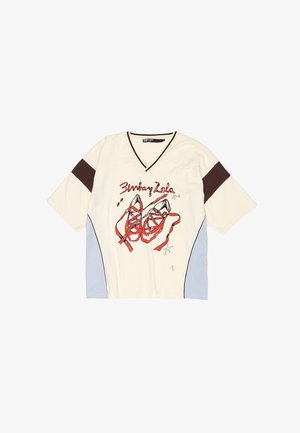 Krémová košeľa s krátkymi rukávmi a výstrihom do V, s grafickým zobrazením červených baletných topánok, hnedými ramennými akcentmi a svetlomodrými bočnými panelmi.