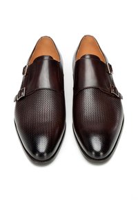 Paar dunkelbrauner Ledermonk-Strap-Dressschuhe mit strukturiertem Zehenbereich und doppelten silbernen Schnallen, von oben auf weißem Hintergrund gezeigt.