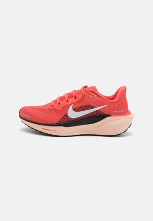Coral pink Nike running shoe with white swoosh, black midsole detail, cushioned peach sole, and breathable knit upper.