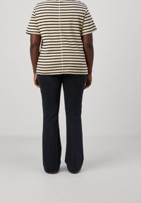 Striped t-shirt in beige and navy, short sleeves, with a central seam. Paired with dark flared jeans. Back view, smooth fabric.