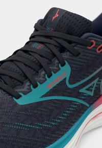 Dark navy running shoe with a mesh upper, teal accents, and red logo. Features flat laces and cushioned sole in white and pink.