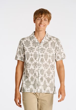 Camisa de botones de manga corta con un fondo color crema claro, que presenta intrincados patrones florales y de paisley en verde a lo largo.