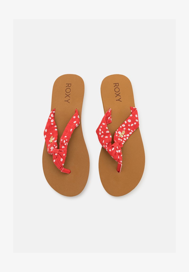 Chinelas de tecido vermelho com padrões florais, tiras atadas e solas texturizadas castanhas com a marca "ROXY" em relevo.
