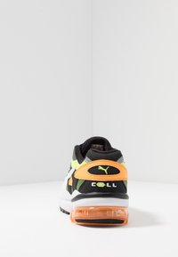 Svart och grön sportskor med en orange accent och genomskinlig häl. Har nätöverkärl, vadderad krage och logodetalj.