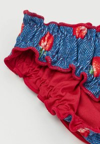 Rynkad baddräktstyg har ett blått denimmönster med röda jordgubbar, accentuerat med en livlig röd foder och sömmar.