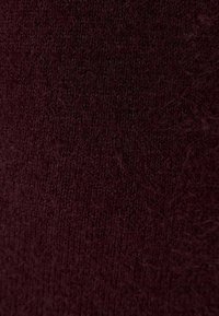 Burgundy stickad tyg med en mjuk, texturerad yta, som har en fin, tät väv och ett något luddigt utseende.