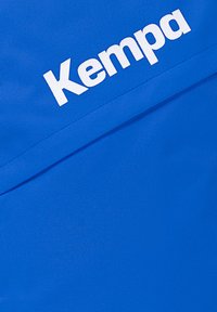 Blauwe textuurstof met een gladde afwerking, met opvallende witte "Kempa" branding aan de bovenkant. Eenvoudig en functioneel ontwerp.