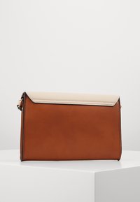 Ruskea nahkainen clutch-laukkua, jossa on vaaleankermanvärinen läppä, tyyliltään sileä ja kontrastiväriset saumat. Kompakti suorakulmainen muoto.