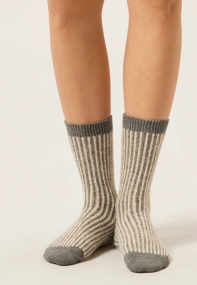 Chaussettes à rayures avec une base crème et des rayures verticales grises et beiges. Poignet supérieur côtelé et orteil renforcé de couleur gris uni.