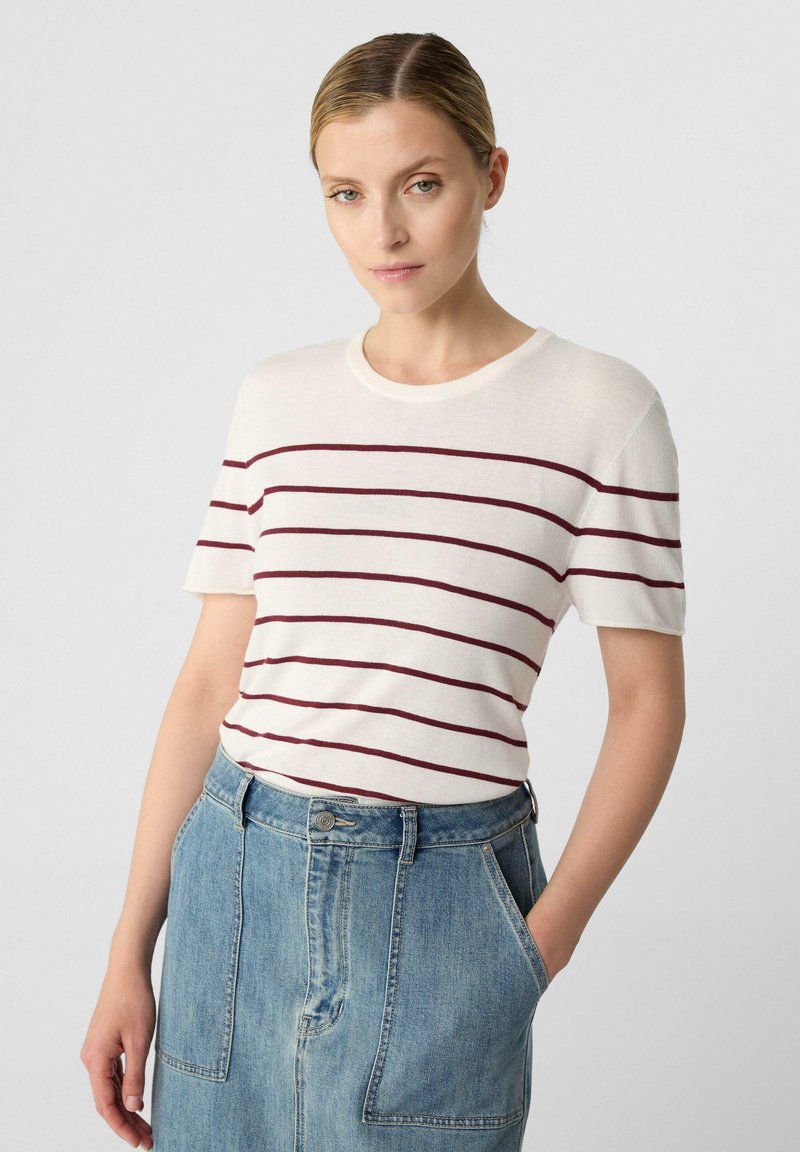 Gestreiftes kurzärmeliges T-Shirt in Creme mit kastanienbraunen Streifen, runder Ausschnitt, kombiniert mit einem taillenhohen Jeansrock mit Fronttaschen.