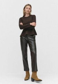 Brązowy prążkowany sweter z rozkloszowanym dołem połączony z błyszczącymi czarnymi spodniami z sztucznej skóry oraz beżowymi zamszowymi botkami za kostkę na słupku.