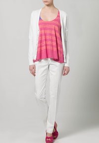 Biały kardigan na różowym topie na ramiączkach w poziome paski, połączony z białymi spodniami i różowymi sandałami na platformie. Gładkie tekstury, swobodny krój.