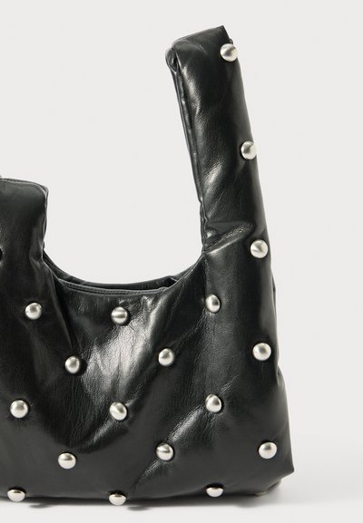 Bolsa de couro preto com um design macio e acolchoado, decorada com tachas prateadas dispostas uniformemente pela superfície e uma alça curta e resistente.
