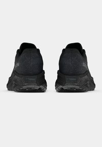 Ζευγάρι μαύρα παπούτσια τρεξίματος Salomon, εμφανιζόμενα από πίσω, με υφασμένες μεσαίες σόλες και σήμανση "energy eva FOAM" στις φτέρνες.