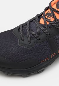 Black textured fabric athletic shoe with orange accents, features reinforced toe and mesh panels, laced design, and rugged sole.