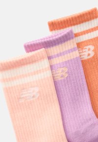 Τρία ζευγάρια ριχτών καλτσών σε απαλά χρώματα: ροδακινί, λεβάντα και πορτοκαλί, με λευκή ρίγα και μικρό λογότυπο New Balance.