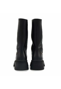 Bottes noires en cuir jusqu'au genou avec un panneau texturé, semelle plate en caoutchouc et un accent en métal rond à l'arrière.