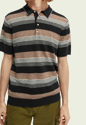Personne portant un polo à manches courtes avec des rayures horizontales noires, marron et blanches et un pantalon cargo vert olive.