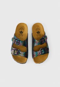 Pár otvorených šľapiek s hnedými stielkami a čiernymi popruhmi, ktoré majú farebné hviezdičkové vzory a každé z nich má dve nastaviteľné spony.