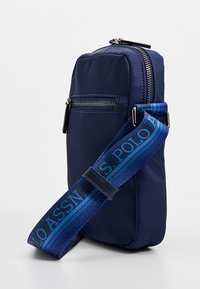 Merensininen nailonlaukku, jossa on etutaskun vetoketju, säädettävä raidallinen olkahihna logolla, suorakaiteen muotoinen ja sileä pinta.