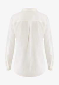 Blusa bianca a maniche lunghe con colletto, caratterizzata da una piega centrale sul retro e polsini abbottonati. Tessuto liscio con una leggera lucentezza.