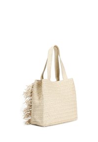 Woven straw tote bag in beige with long textured fringe on one side. Features two sturdy handles and a structured rectangular shape.