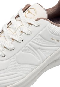 Fehér sneaker texturált gumimaterialból, párnázott barna szegéllyel, fűzős kialakítással és domború részletekkel. Az oldalán "DUO-TEX" címke található.