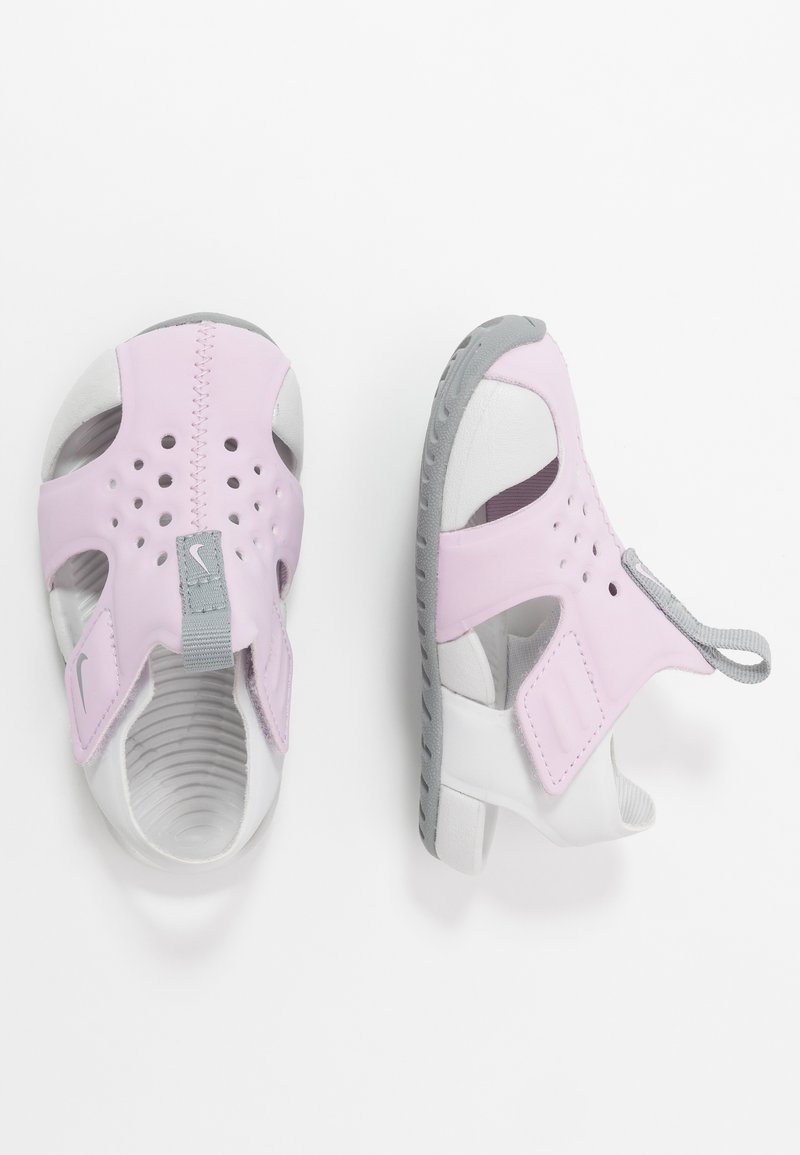Sandali rosa e bianchi con design aperto, realizzati in materiale flessibile. Presentano perforazioni, una fascia grigia e una suola testurizzata per una buona aderenza.